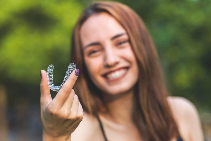 jeune femme tient dans les mains dentier invisalign